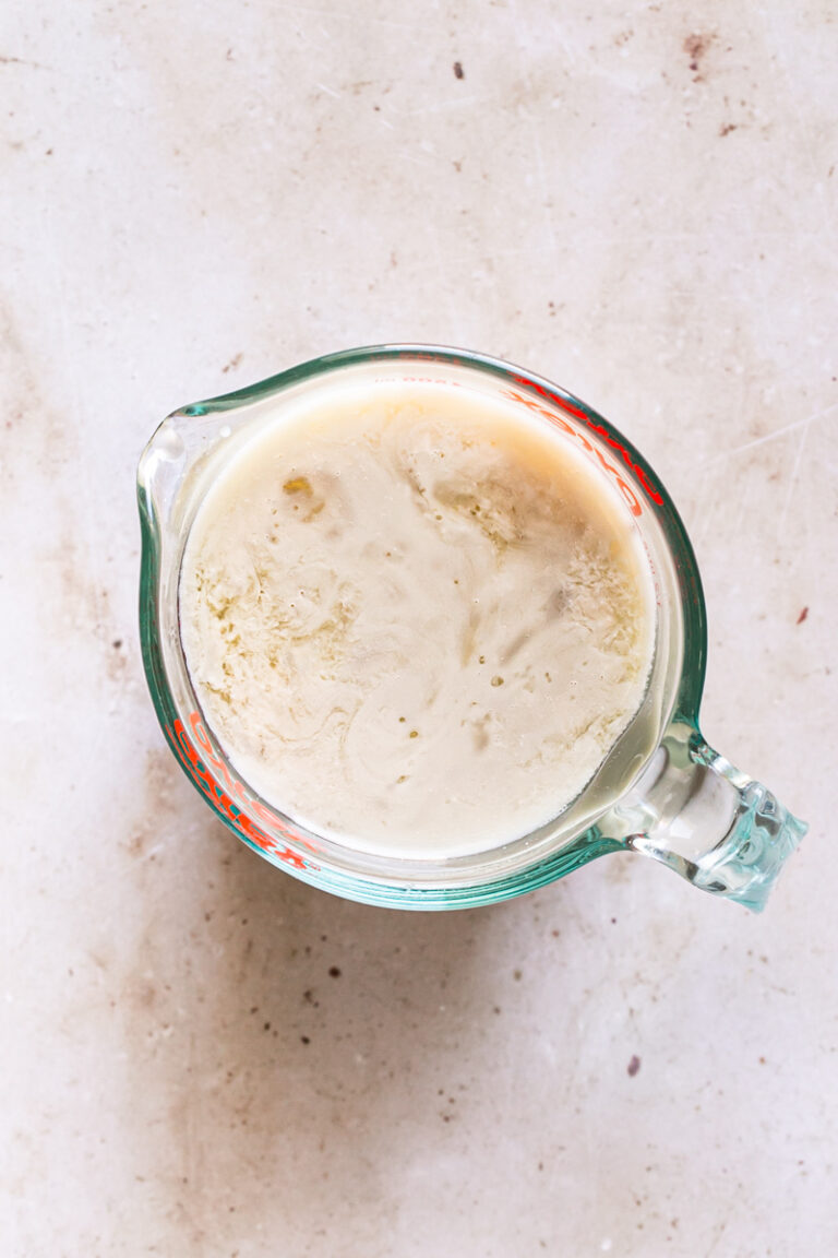a glass measuring cup filled with flax milk mixed with apple cider vinegar
