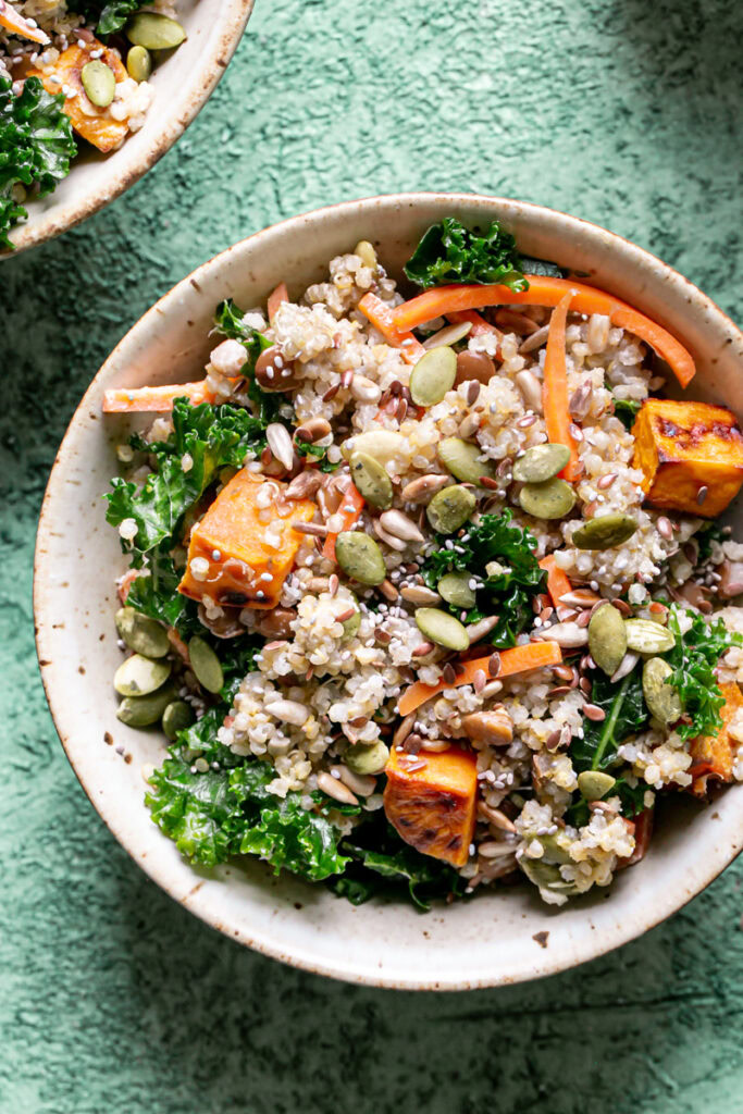 close up of a bowl of Protein Packed Creamy Tahini Quinoa Bowl on a green backdrop