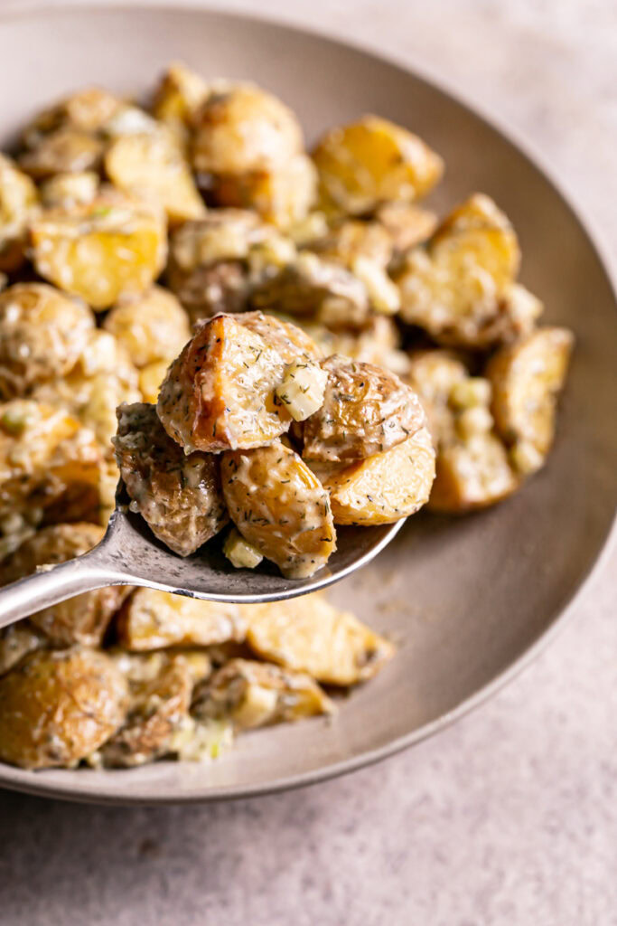 a close up of roasted caesar potato salad on a spoon