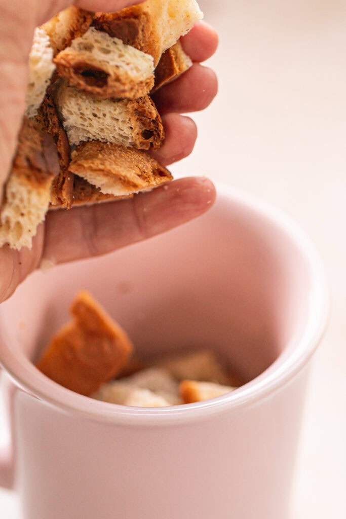 action shot of placing the bread chunks into the mug