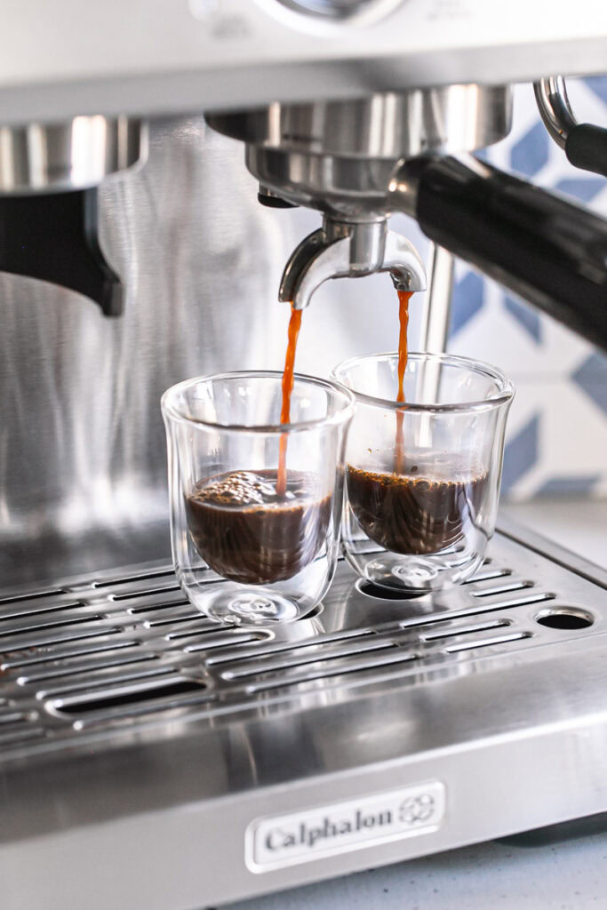 action shot of brewing a shot of espresso into two espresso glasses