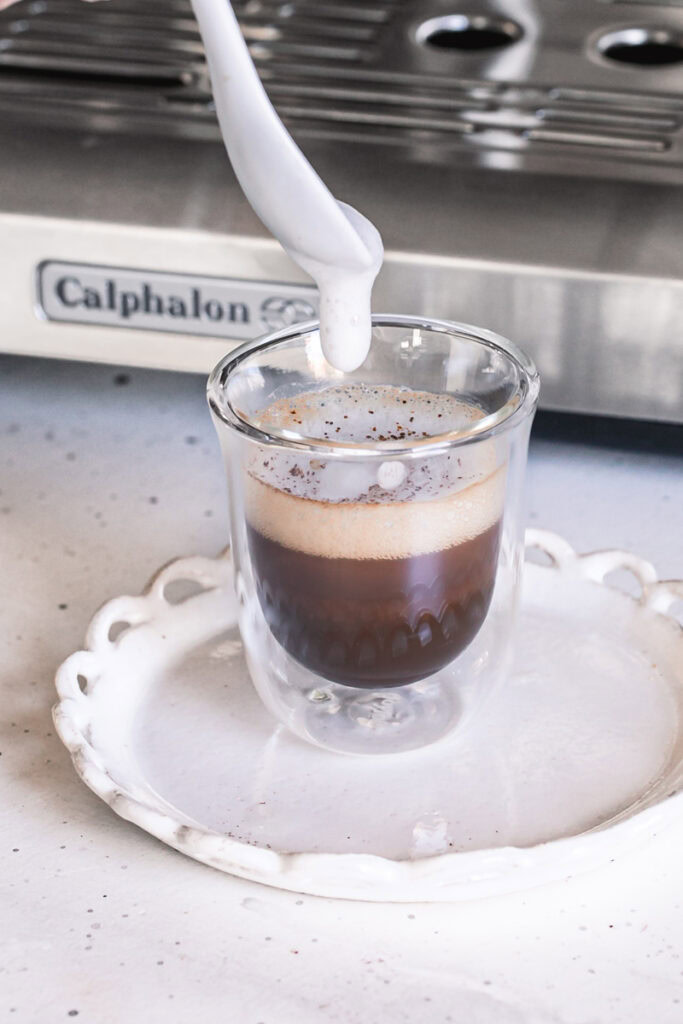 spooning the steamed milk over top of the brewed espresso