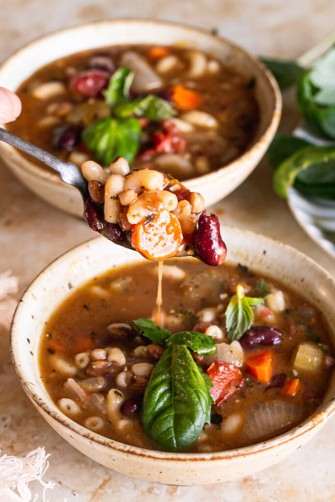 action shot of spooning some minestrone soup out of the bowl