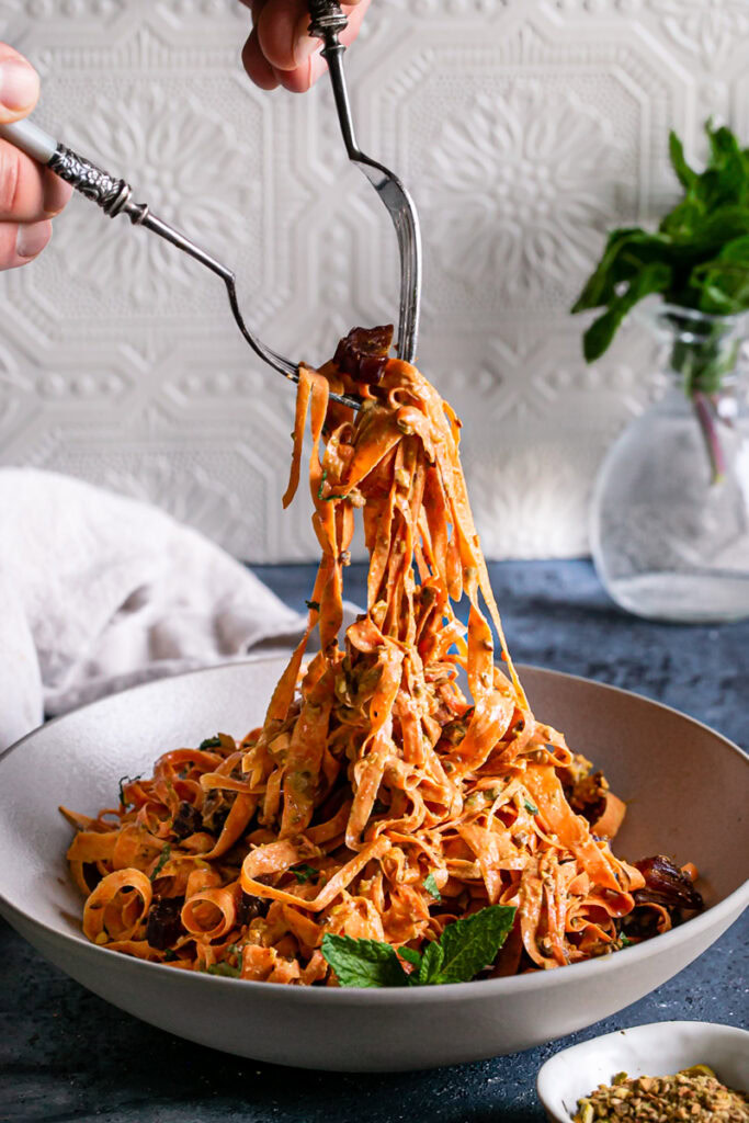 pulling the raw carrot salad out of the bowl with two forks, like pasta