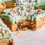 a close up shot of a vegan gluten free frosted cookie dough square with a bite taken out of it