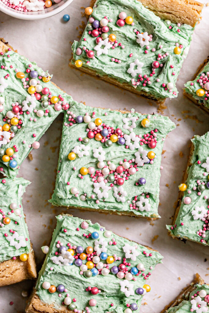 close up overhead shot of green frosted cookie bars decorated with sprinkles cut into squares