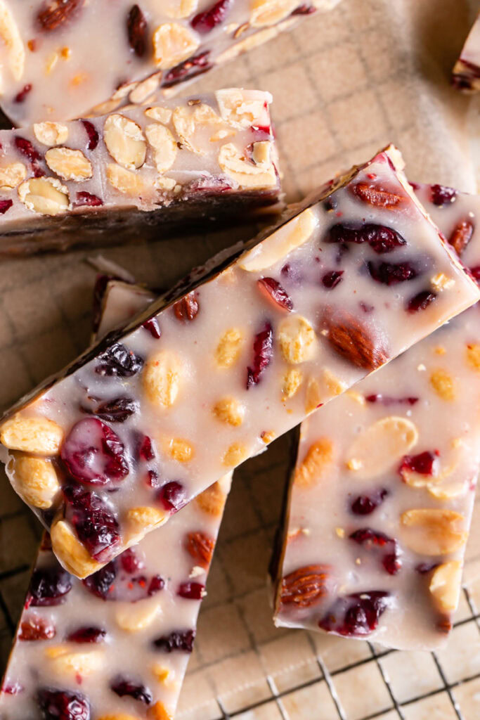 close up of sliced White Chocolate Amaretto Trail Mix Truffle Bars on a parchment square on a rectangle cooling rack