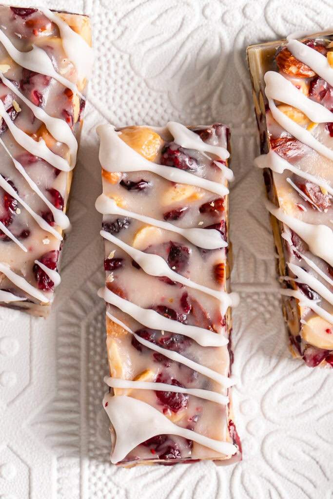 three White Chocolate Amaretto Trail Mix Truffle Bars next to us drizzled with dairy-free white chocolate
