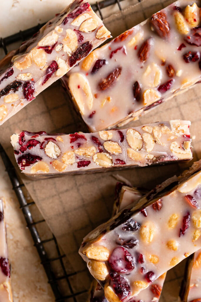 close up of sliced White Chocolate Amaretto Trail Mix Truffle Bars on a parchment square on a rectangle cooling rack