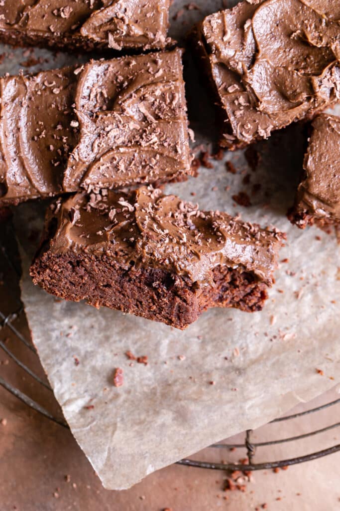 close up of a butternut squash brownie frosted with chocolate avocado frosting with a bite taken out of it, turned on its side