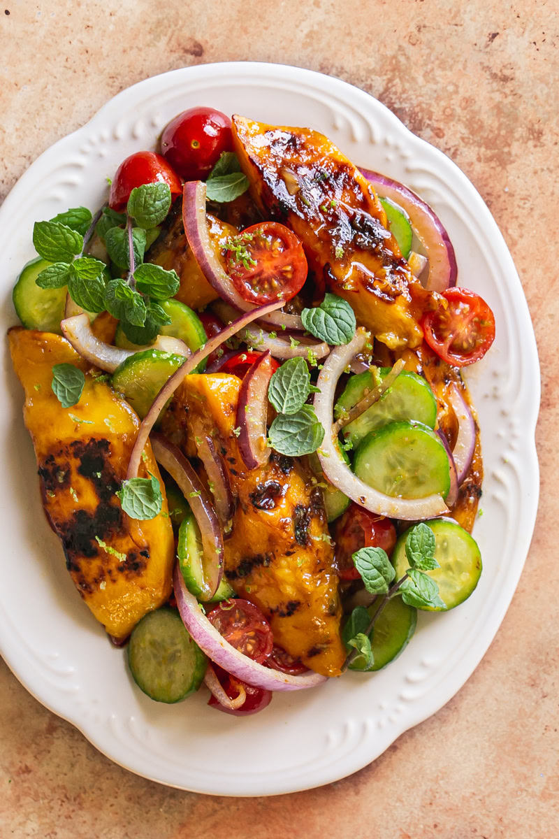 grilled mango sweet chili lime salad on a white scalloped plate garnished with fresh mint
