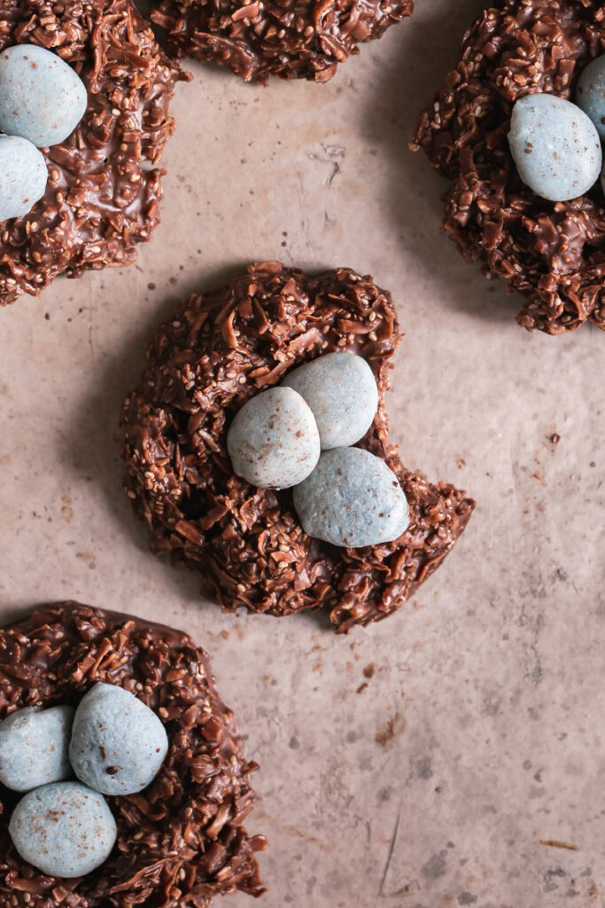 5 Toasted Coconut Chocolate Bird's Egg Nest Cookies filled with three robin's egg white chocolate covered almonds in each nest, the middle cookie with a bite taken out of it