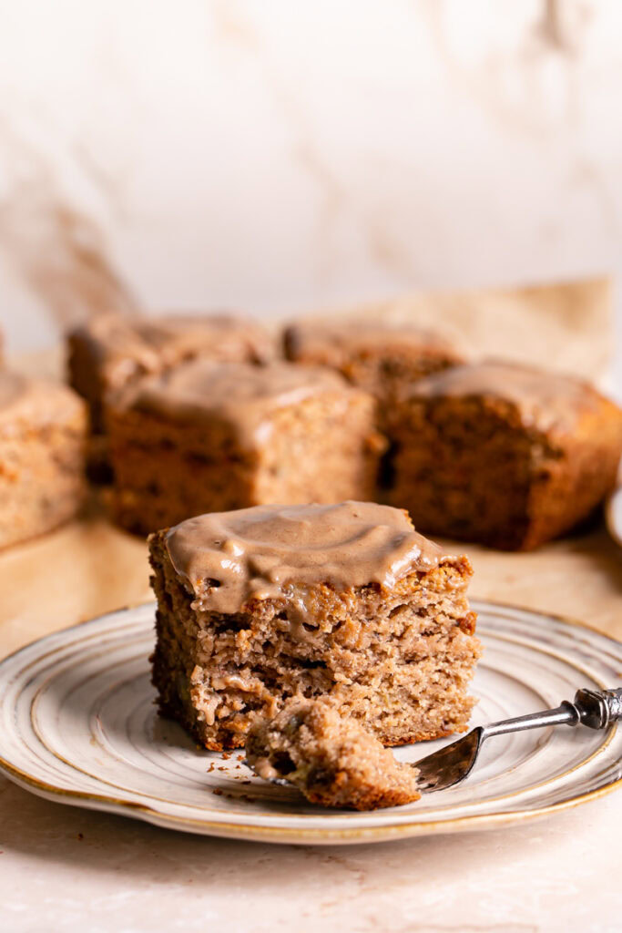 a piece of maple tahini banana bread bar on a plate with some on a fork and the other slices in the background