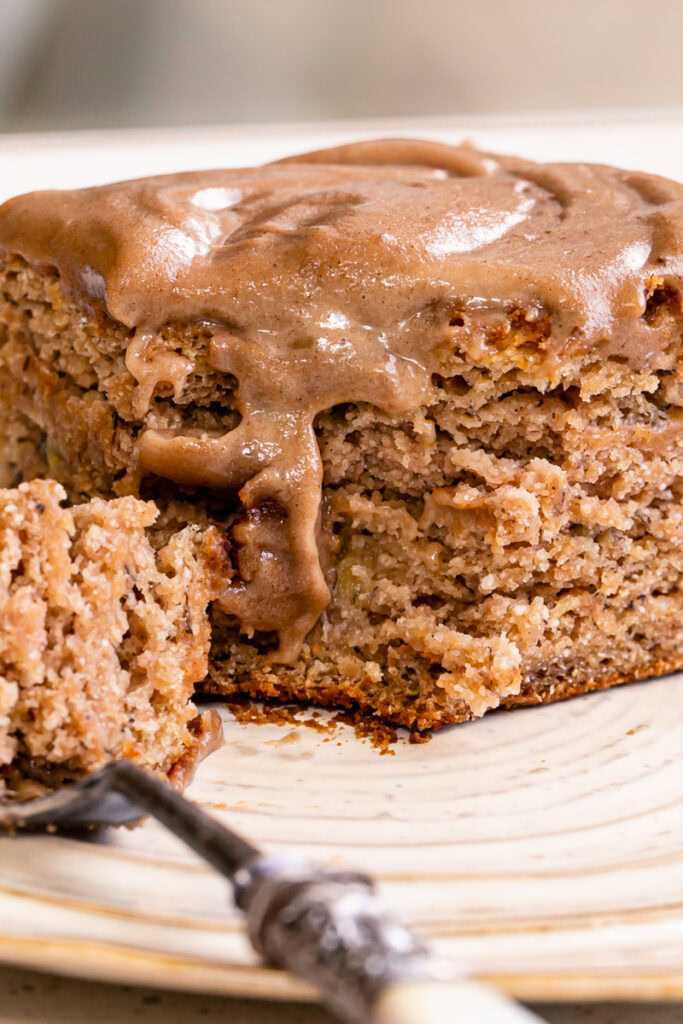 a very close up shot of a piece of maple tahini banana bread bar on a plate with some on a fork
