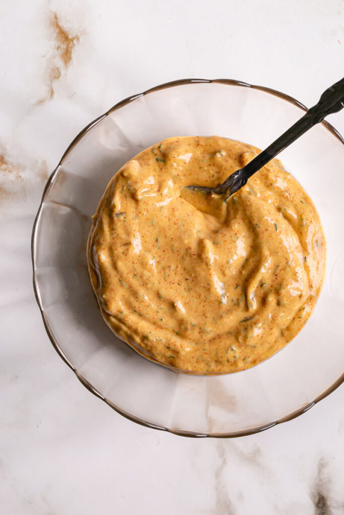 a bowl of homemade dressing made with vegan mayo, sweet relish, dried dill, garlic powder, onion powder, smoked paprika, and yellow mustard