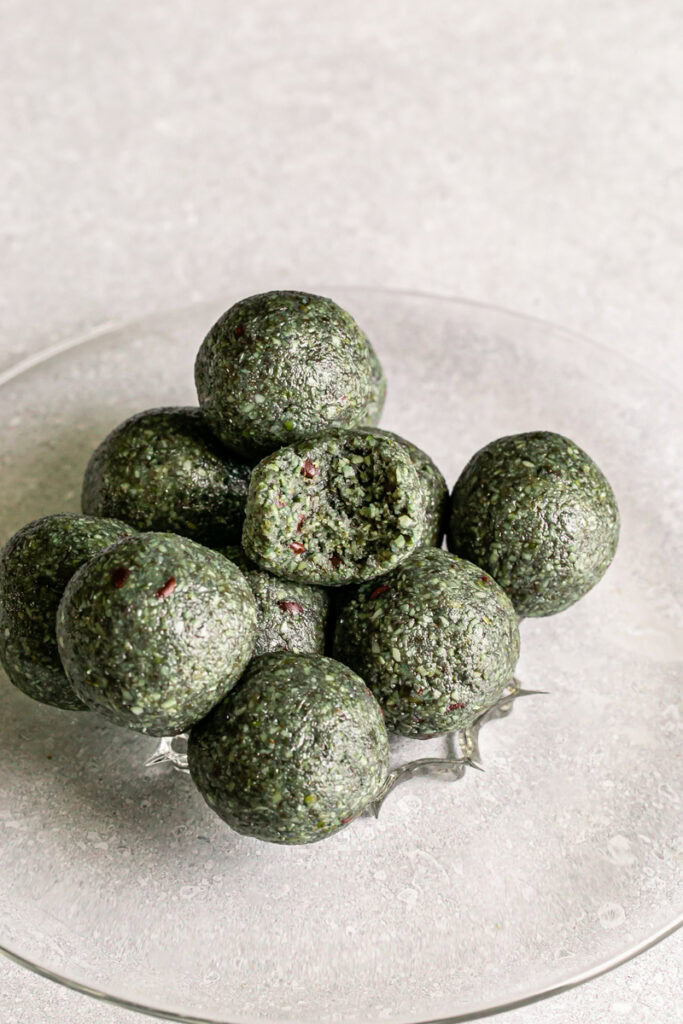 Spirulina Pumpkin Seed Chocolate Chip Bites stacked on top of one another, one with a bite taken out of it