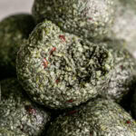 close up macro shot of Spirulina Pumpkin Seed Chocolate Chip Bites with a bite out of the middle one