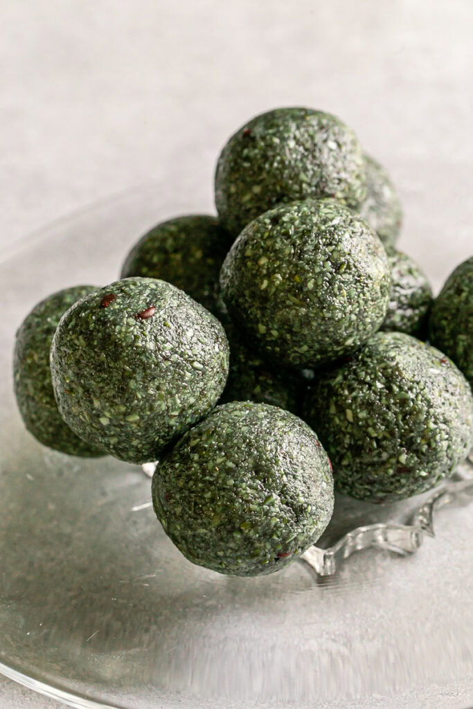 Spirulina Pumpkin Seed Chocolate Chip Bites stacked on top of one another on a glass plate
