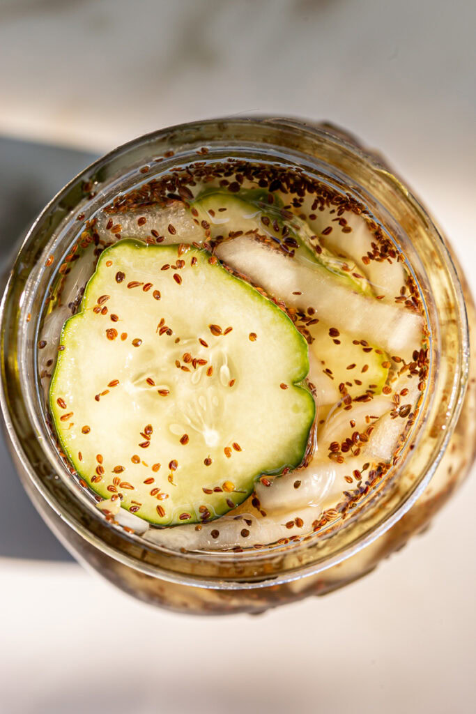 overhead shot of sliced cucumber and onion in a canning jar