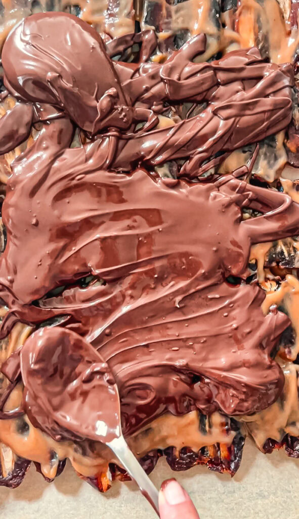 action shot of spreading melted chocolate over the caramel covered dates