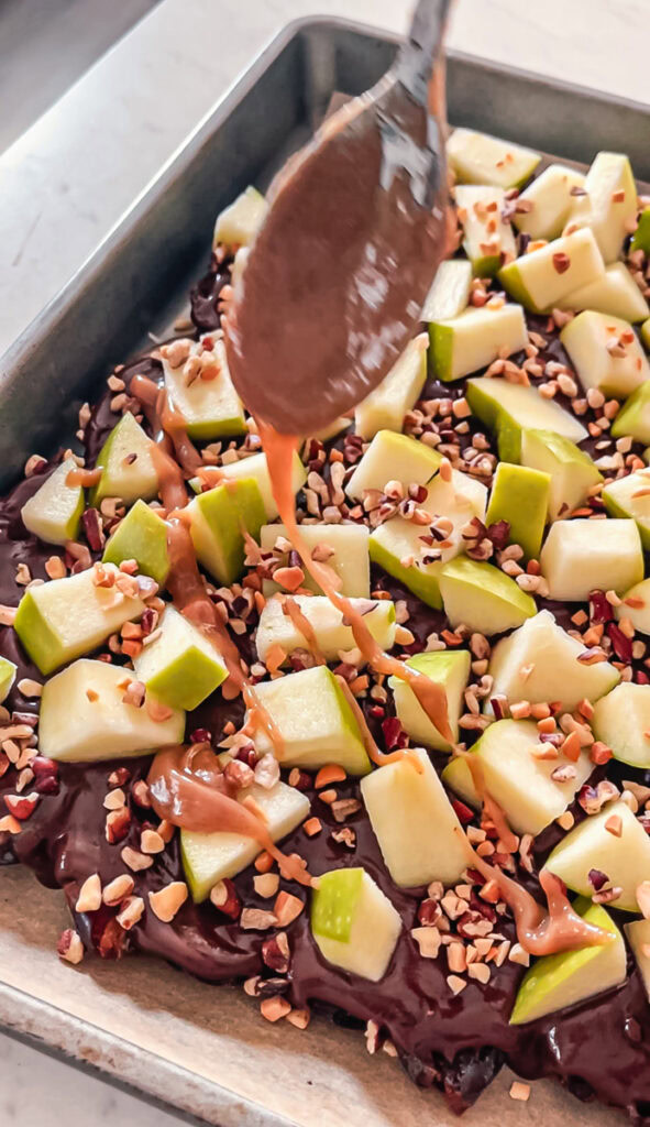 action shot of drizzling peanut butter caramel over the date bark