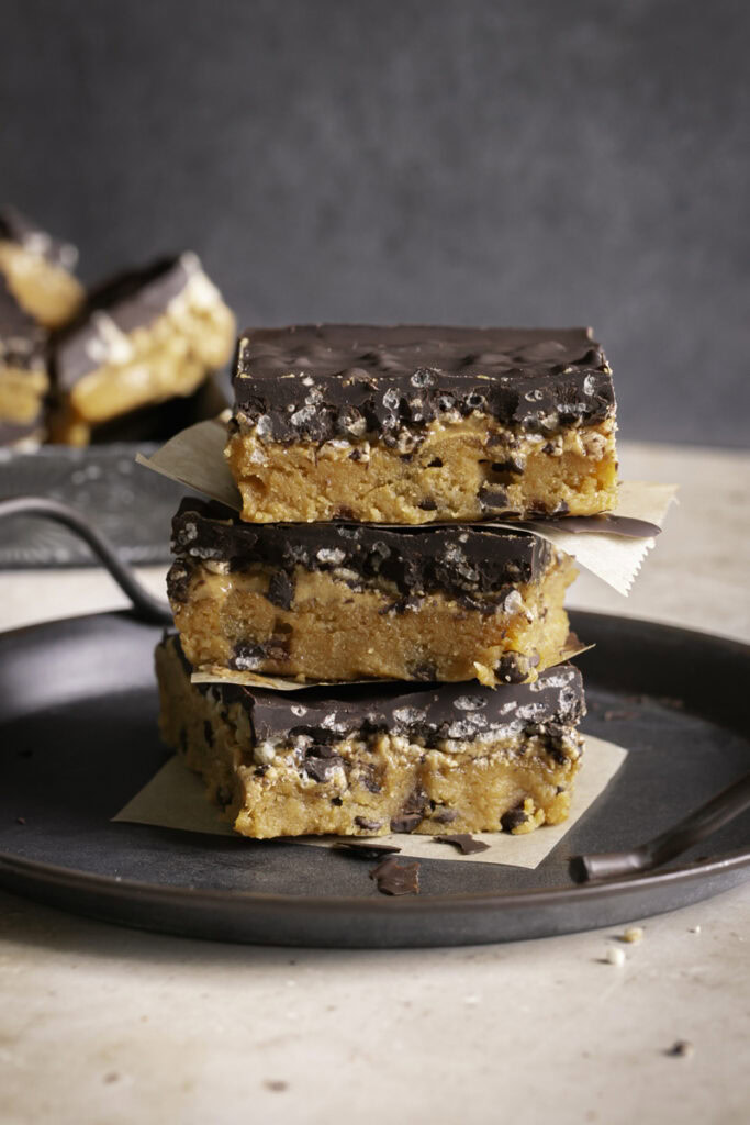 Three Almond Flour Pumpkin Cookie Dough Crunch Bars stacked on top of one another on a round metal plate with handles