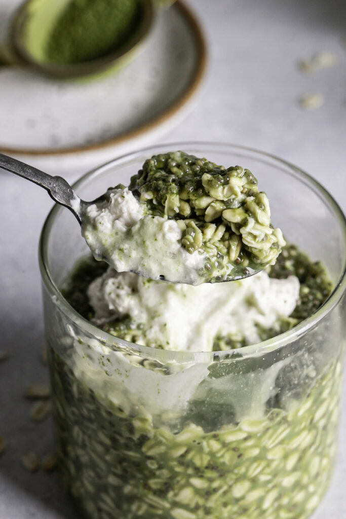 a close up of a spoon scooping some Oat Milk Matcha Latte Overnight Oats out of a glass