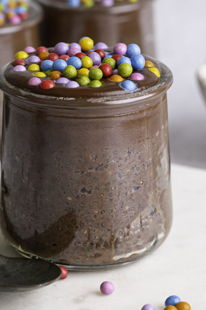 a very close up image of a jar of a jar of Cosmic Brownie Chocolate Chia Seed Pudding with two more jars blurred in the background.