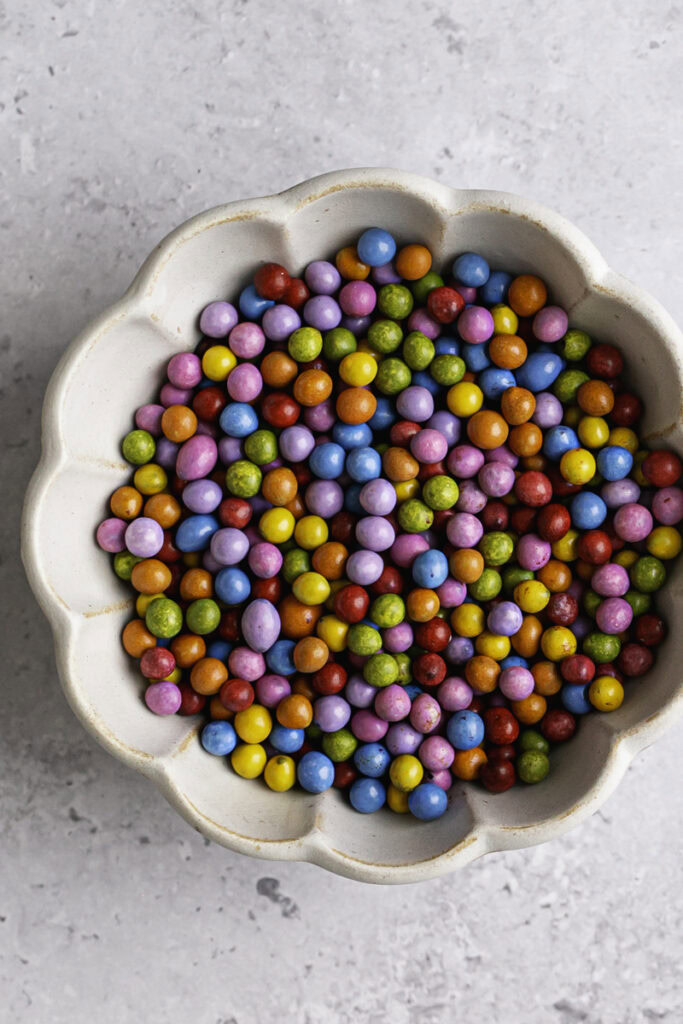 a small bowl filled with rainbow candy coated chocolate chips.