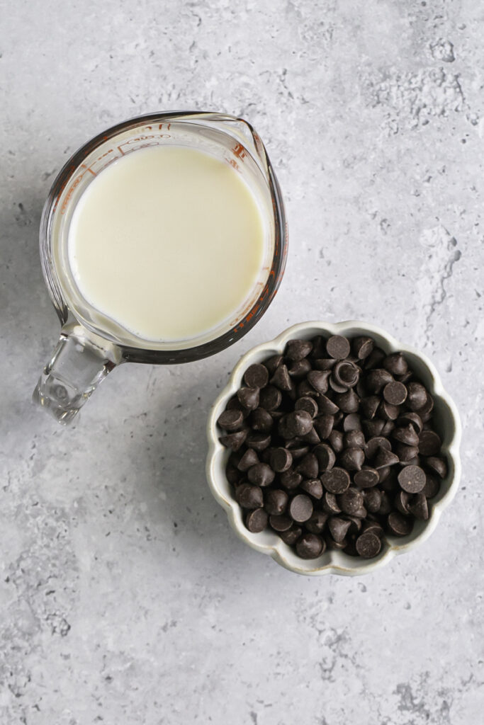 plant milk in a glass measuring cup and dark chocolate chips in a small bowl.
