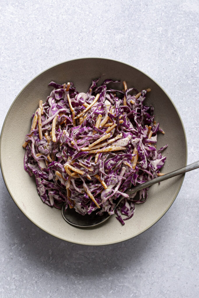 overhead photo of red cabbage coleslaw in a bowl with a spoon sticking out.