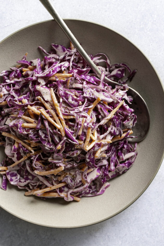 overhead photo of red cabbage coleslaw in a bowl with a spoon sticking out.