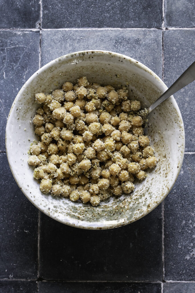 chickpeas in a bowl mixed with gluten-free breadcrumbs and a spoon sticking out of the bowl.