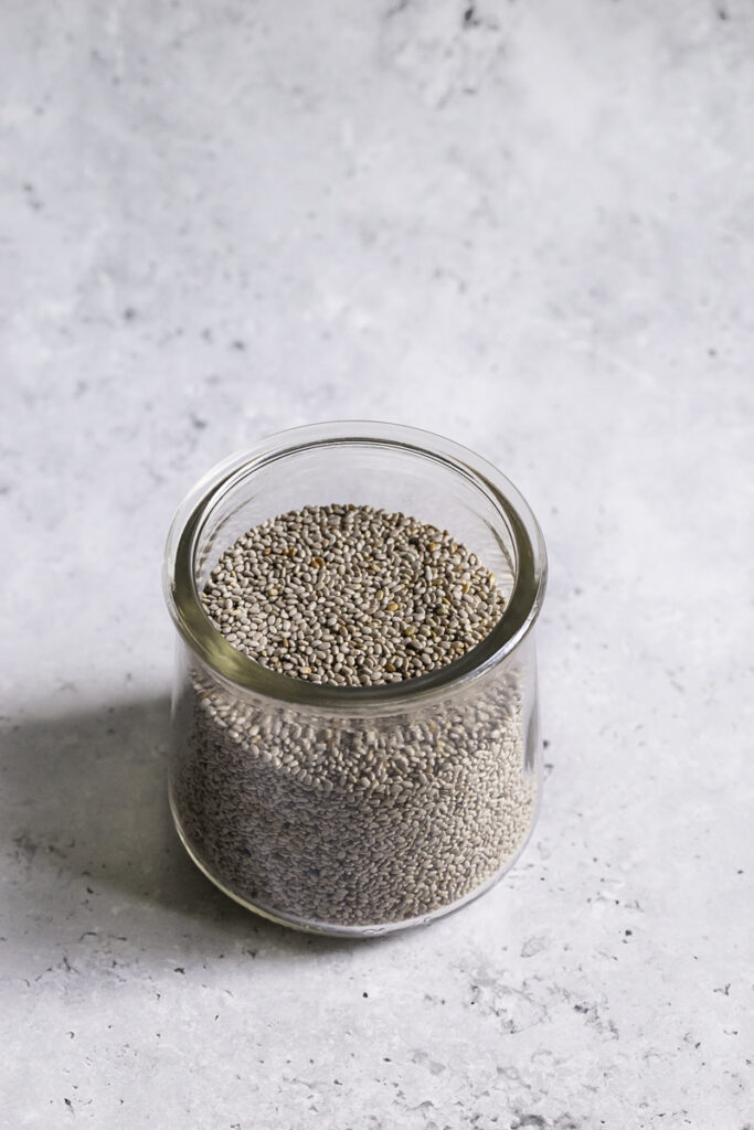an overhead shot of white chia seeds in a glass jar.