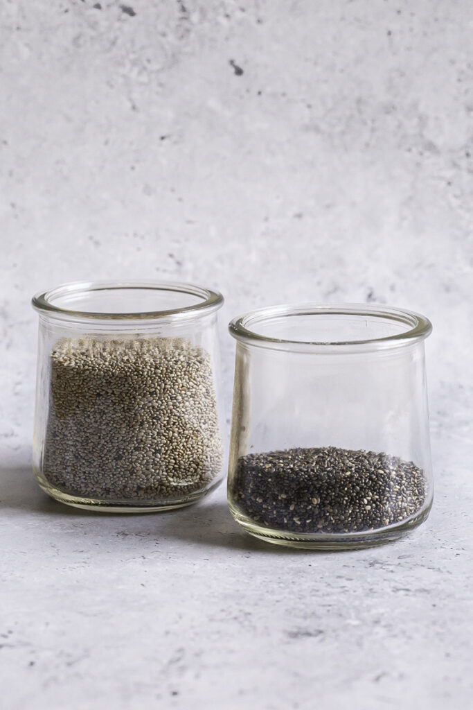 a glass jar of white chia seeds and a glass jar of black chia seeds.