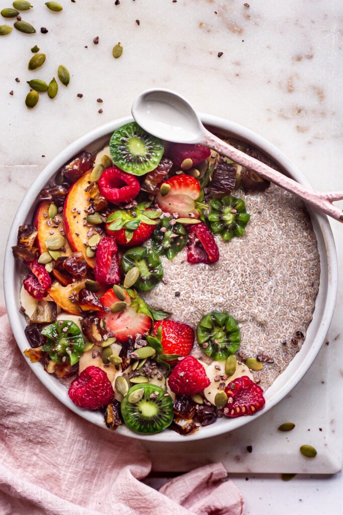a bowl of chia pudding topped with kiwi, raspberries, and peaches.