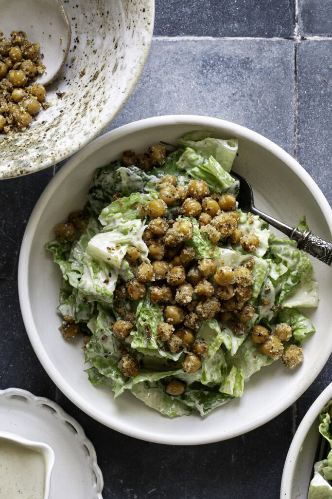 close up overhead shot of romaine caesar salad garnished with crispy chickpea croutons.