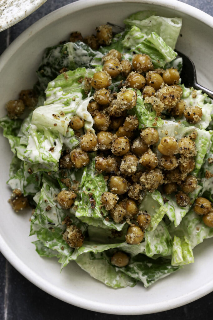 close up overhead shot of romaine caesar salad garnished with crispy chickpea croutons.