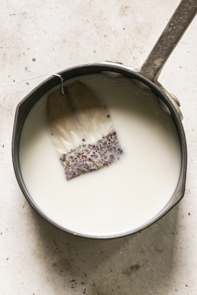 a strawberry hibiscus tea bag steeping in a small saucepan filled with flax milk.