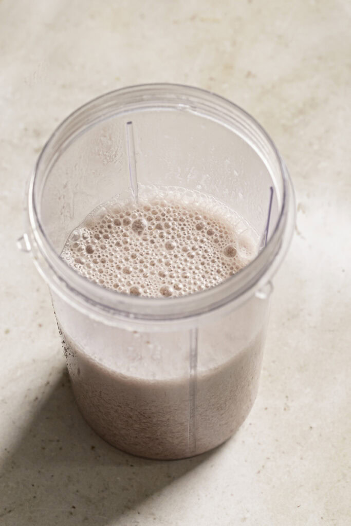 strawberry hibiscus milk blended with 3 small strawberries in a glass.