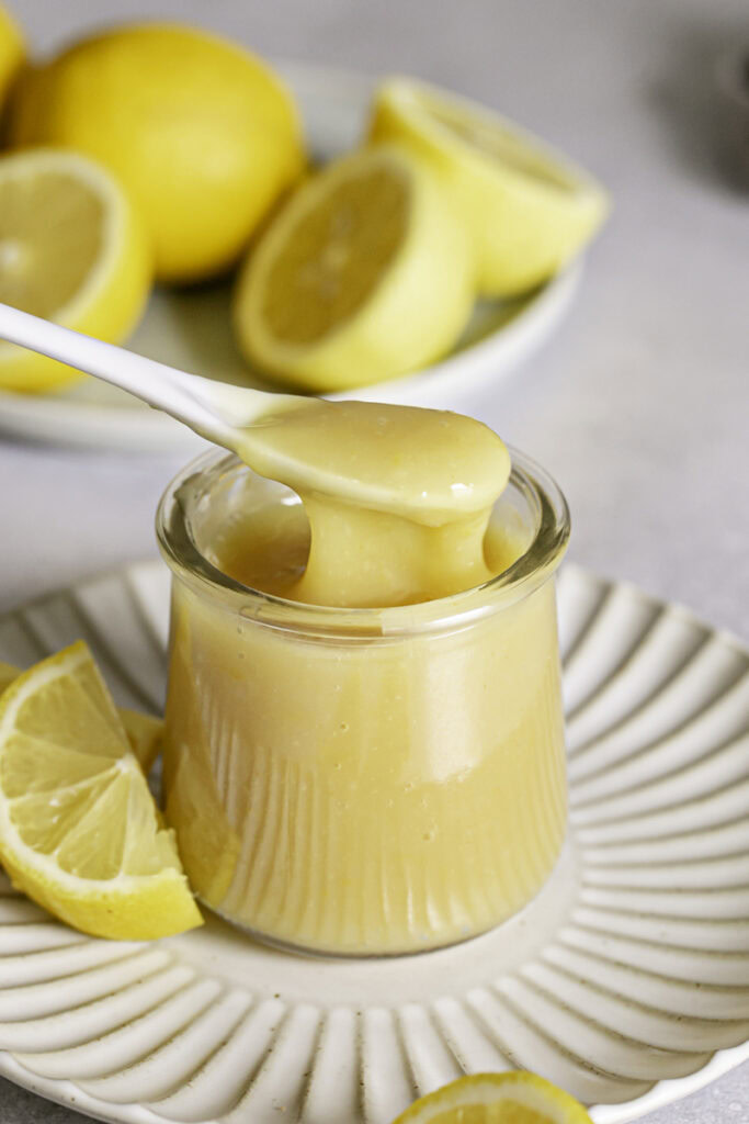 action shot of spooning some lemon curd out of the jar.