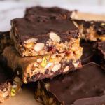 sliced trail mix bars stacked on top of each other on a piece of parchment paper.