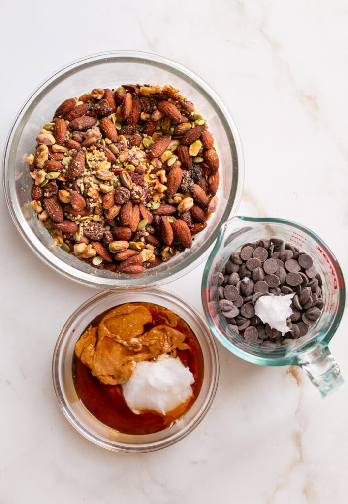 all the ingredients used to make trail mix bars in separate bowls.