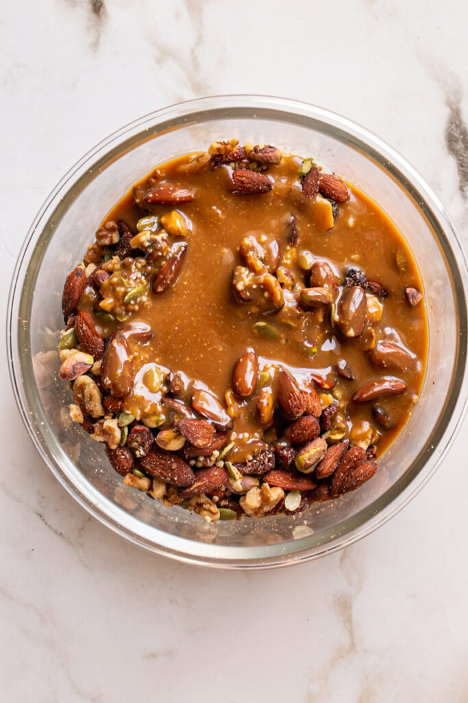 the melted peanut butter mixture poured over the mixed nuts and seeds.