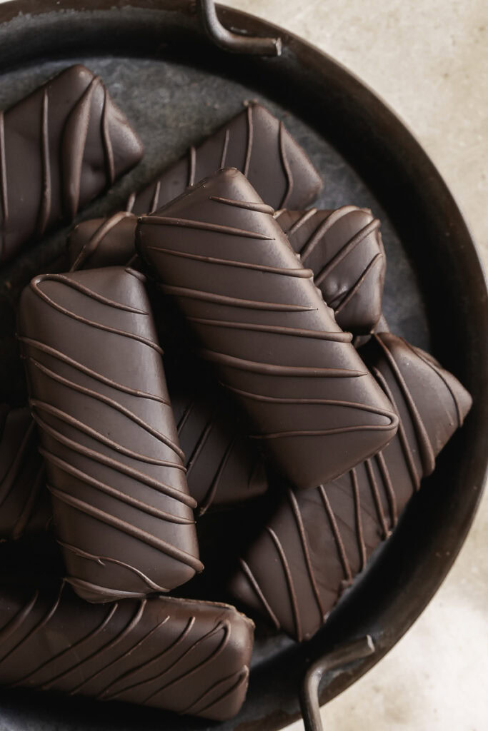 overhead close up shot of crispy peanut butter protein chocolate candy bars stacked on an enamel plate.