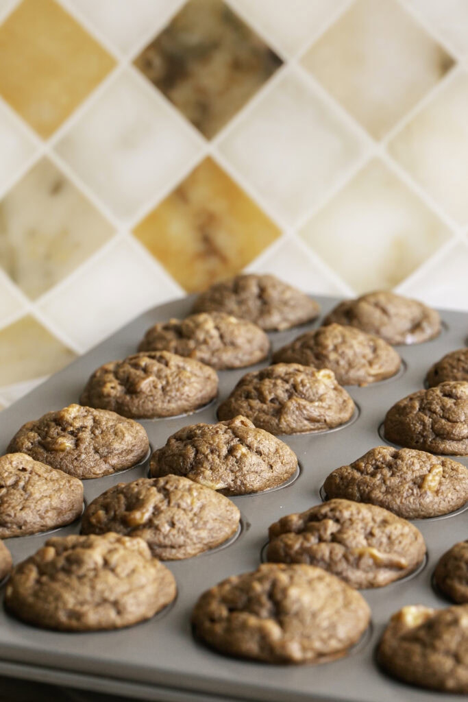 baked mini apple cider banana bread muffins in a muffin pan.