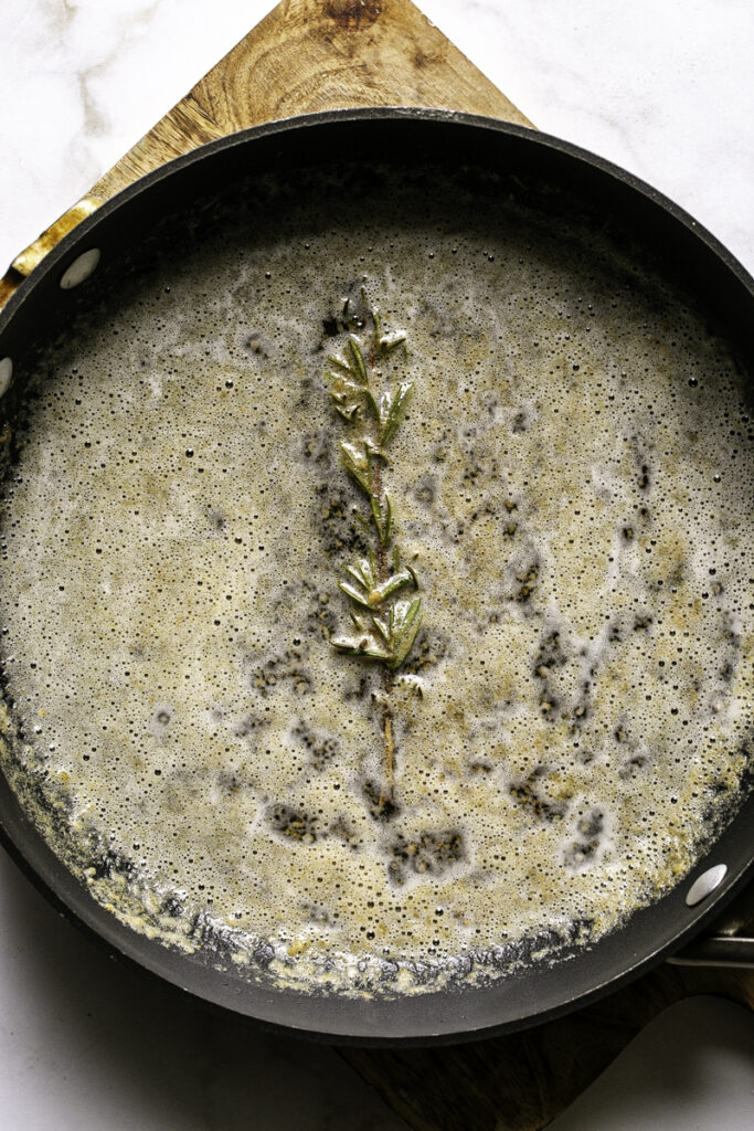 melted butter, a sprig of rosemary, and minced garlic in a skillet.