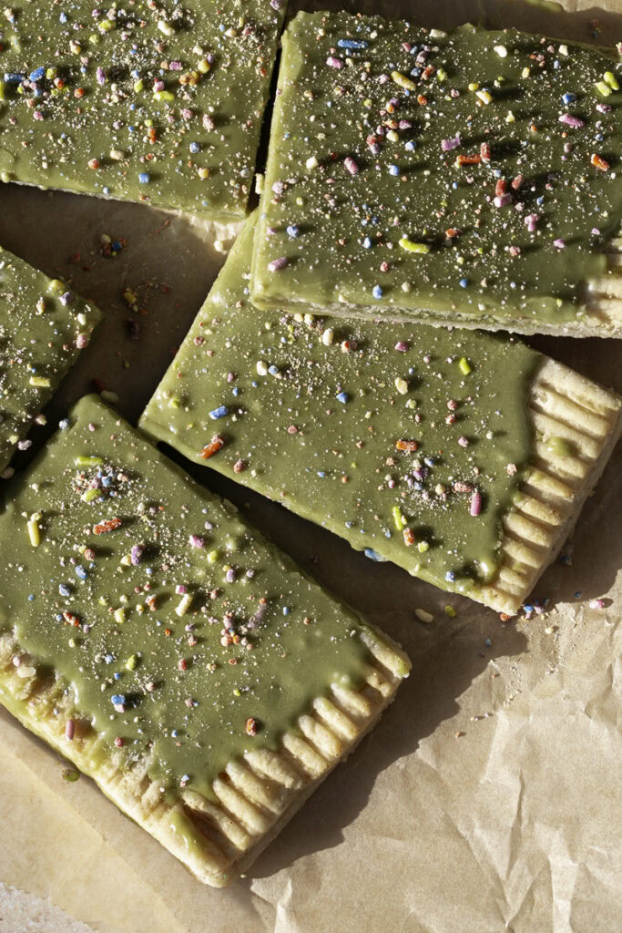 close up of cut slices of a giant frosted matcha pop tart decorated with sprinkles.