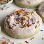 3/4 shot of soft frosted and sprinkled sugar cookies and a bowl of sprinkles.
