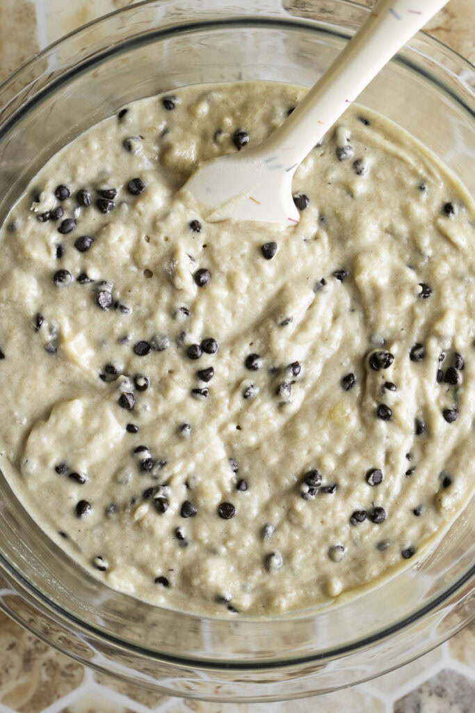 overhead shot of mini buckwheat flour chocolate chip banana muffin batter in a bowl with a spatula.